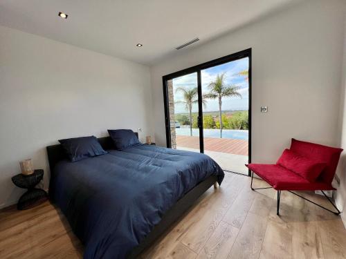 une chambre avec un grand lit et une chaise rouge dans l'établissement Villa d’exception avec piscine à débordement - vue panoramique, à Saint-Nazaire