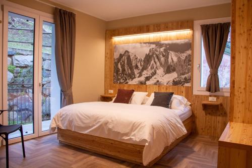 a bedroom with a bed with a mountain picture on the wall at Garni Le Grigne in Barzio