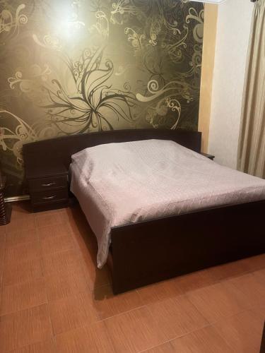a bed in a bedroom with a wall with a flower pattern at Nelly's Home in Yerevan