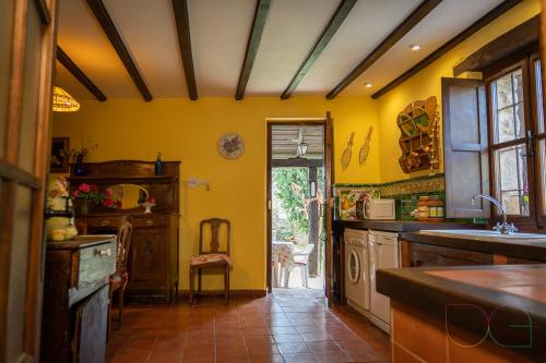 a kitchen with yellow walls and a table and a sink at La Casa de Salinas in Salinas de Pisuerga