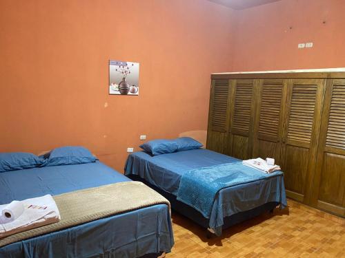 Duas camas num quarto com paredes cor de laranja em Ciudad Vieja Bed & Breakfast Hotel em Guatemala