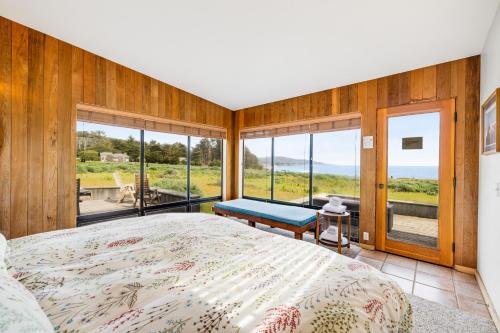 a bedroom with a large bed and large windows at Aloha House in Sea Ranch