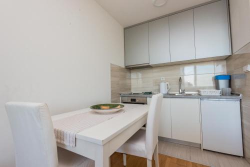 - une cuisine avec des placards blancs, une table et des chaises dans l'établissement HAFSA apartments Sarajevo City view, à Sarajevo