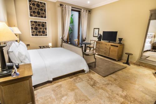 a bedroom with a bed and a desk and a television at Bastión Luxury Hotel in Cartagena de Indias