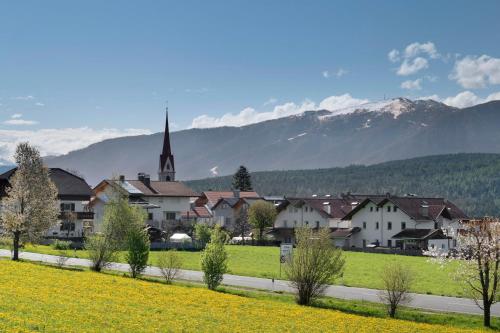 a town with a church and mountains in the background at Stiflerhof Apt Alpenrose in Falzes