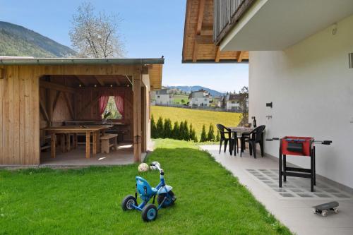 a toy scooter sitting on the grass next to a house at Stiflerhof Apt Enzian in Falzes