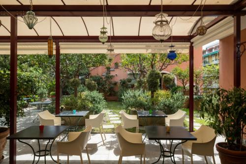 un patio con mesas y sillas y un jardín en Albergo Minerva, en Santa Margherita Ligure