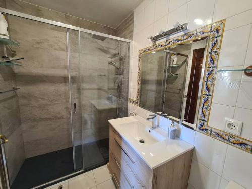 a bathroom with a shower and a sink and a mirror at Acogedor dúplex en urbanización con piscina en Ajo in Ajo