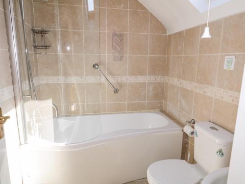 ein Bad mit einer Badewanne und einem WC in der Unterkunft Inverbeg Cottage 1 in Downings