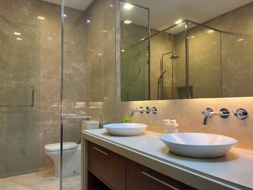 a bathroom with two sinks and a shower and a toilet at 2Beds Seaview Straits Quay comes with Carpark and Hothub in Bagan Jermal