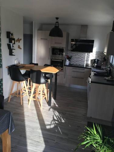 une cuisine avec une table et des chaises dans une pièce dans l'établissement Charmante maison neuve à 2 pas de la mer !!, à Sarzeau