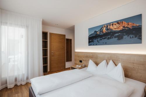 a bedroom with a white bed and a mountain at Residence Mirabell in Colfosco