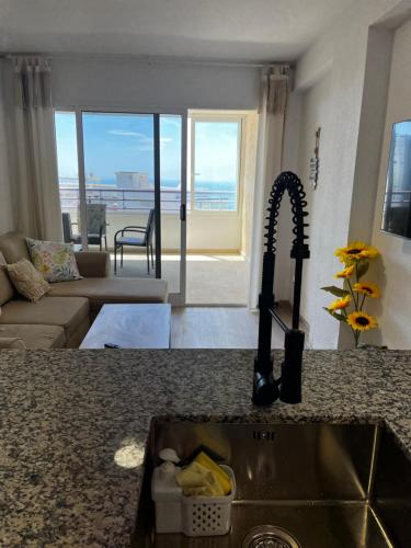 a kitchen counter with a sink and a living room at VERANO AZUL in Benidorm