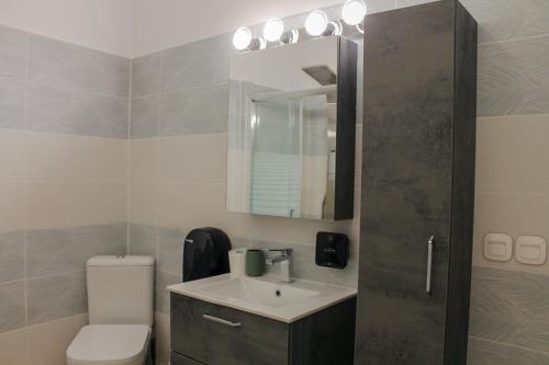 W łazience znajduje się umywalka, toaleta i lustro. w obiekcie Wave Luxury Apartments w Kassiopi