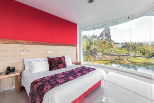 a bedroom with a bed and a large window at Hotel Los Recuerdos in Guatapé