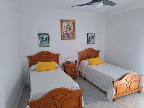 a bedroom with two beds and a ceiling fan at CASA ORIOL in Ayamonte