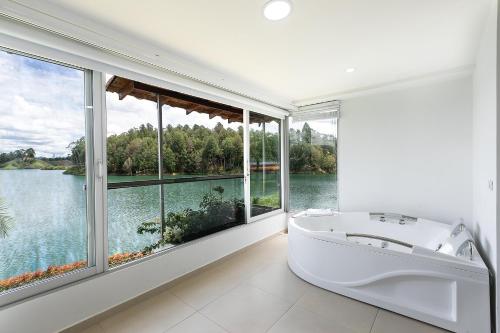 bañera blanca en una habitación con ventanas en Hotel Los Recuerdos en Guatapé