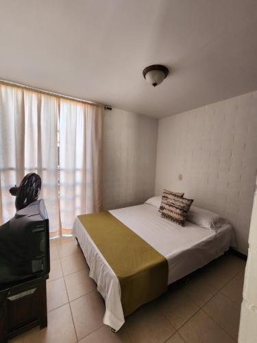 1 dormitorio con 1 cama y TV. en Jardines de Santa Maria, en Cartago