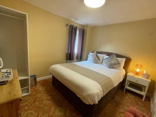 a bedroom with a large bed with white sheets at Fairlight Guesthouse in Glenridding