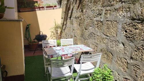 einen Tisch und Stühle neben einer Steinmauer in der Unterkunft Itiseasy Cuglieri 1 e 2 Private Apartments in Cuglieri