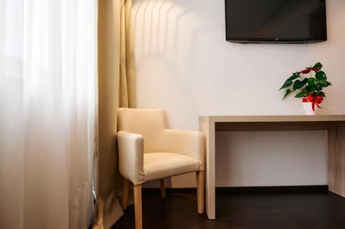 a chair sitting next to a desk with a television at Hotel Meksiko in Ljubljana
