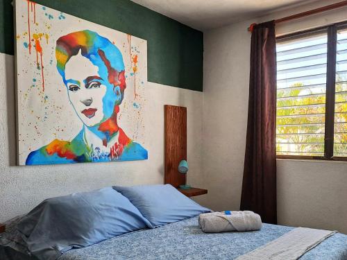 Tu Casa en el Caribe في كانكون: غرفة نوم مع لوحة لامرأة على الحائط