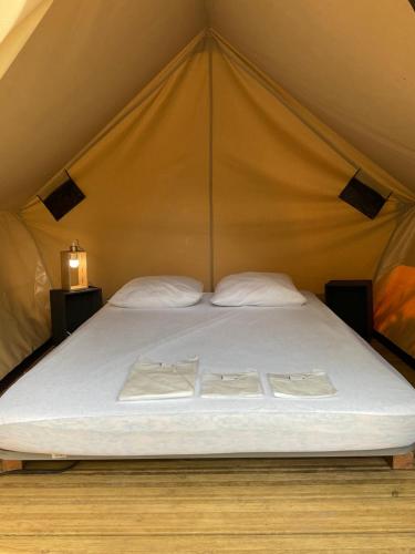 a large bed in a tent with two towels on it at Camping Le Canoë in Chaussin