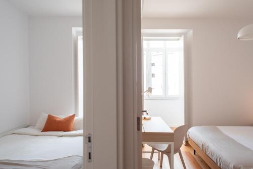 um quarto com 2 camas, uma secretária e uma janela em Amaro II - Sleek 2 bedroom apartment in Alcantara em Lisboa