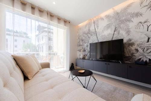 sala de estar con sofá blanco y TV de pantalla plana en KENYA parking gratuit, en Annecy
