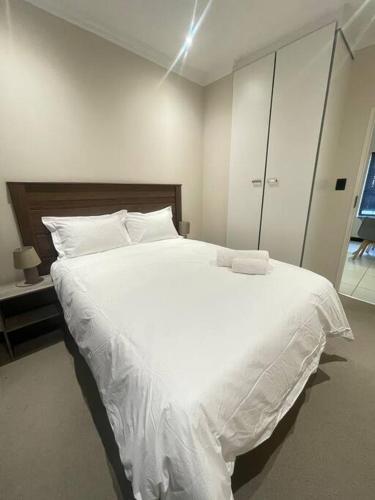 une chambre avec un grand lit blanc avec des draps blancs dans l'établissement Priceless Cove. Garden Cottage, à Midrand