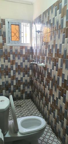 a bathroom with a toilet and a sink and a window at Cozy Nest Résidence in Yaoundé