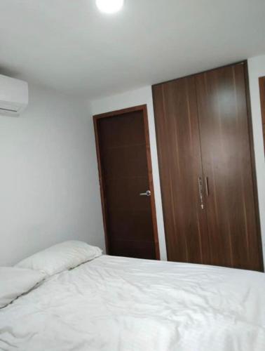 um quarto com uma cama e uma porta de madeira em Bright Duplex 2 bedroom Apartment, kitchen, bathroom & living room em Cartagena de Indias