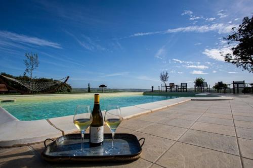 una botella de vino y dos copas junto a la piscina en Agriturismo Re Tarquinio, en Tuscania