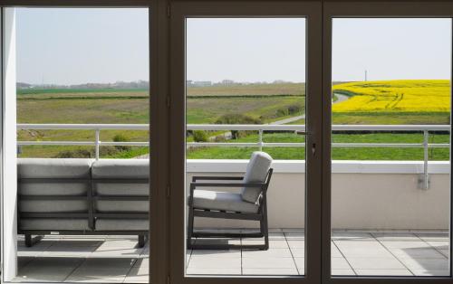 a chair on a balcony with a view of a field at Le Wim' - Appart neuf proche plage et centre ville in Wimille