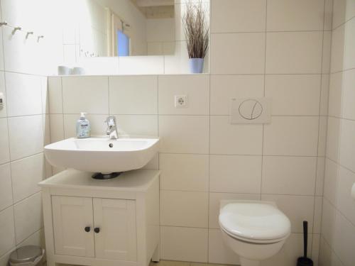 a white bathroom with a sink and a toilet at Ferienhaus Oceansounds in Sierksdorf