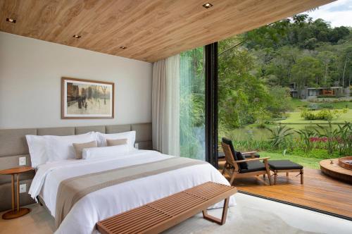 a bedroom with a large bed and a large window at Casa Marambaia Hotel in Petrópolis