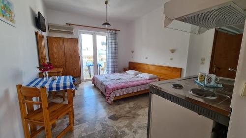 a bedroom with a bed and a kitchen with a table at Studio Bellos in Tolo