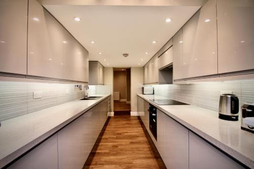 a large kitchen with white cabinets and wooden floors at Mill House Townhouse in Newmarket