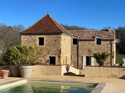 une maison en briques avec une piscine en face de celle-ci dans l'établissement Le Bos Dordogne, à Soulaures