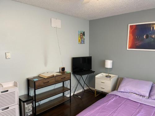 a bedroom with a bed and a desk with a television at Shared Space with Private room in Beautiful Lakefront Apartment in Federal Way