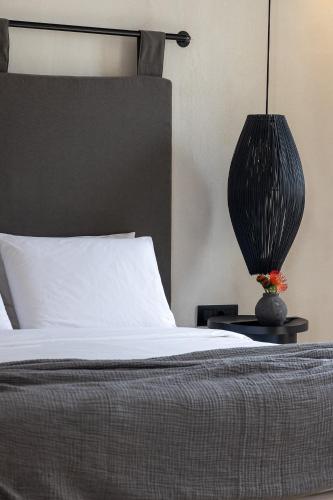 a bedroom with a bed and a lamp on a night stand at Rocabella Mykonos Hotel in Agios Stefanos