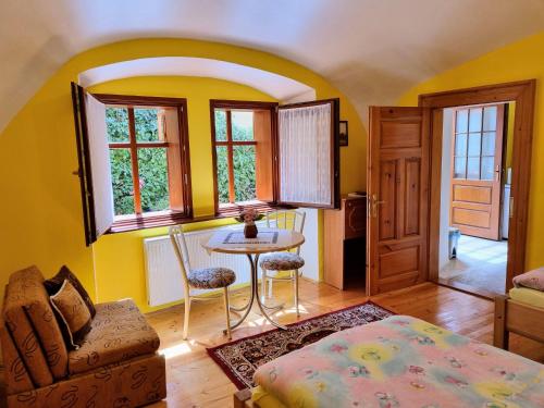 a living room with yellow walls and a table and chairs at Historical house in the center Levoča with parking in Levoča