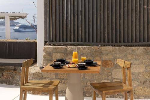a table with two chairs and a table with drinks on it at Rocabella Mykonos Hotel in Agios Stefanos