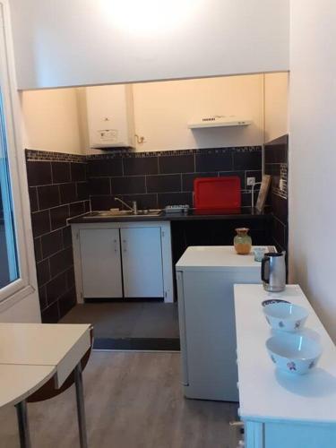 - une petite cuisine avec des placards blancs et du carrelage noir dans l'établissement Appartement 2 chambres à Noisy le grand, à Noisy-le-Grand