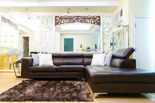 a brown leather couch in a living room at Avant Apartments at The Fort in Manila