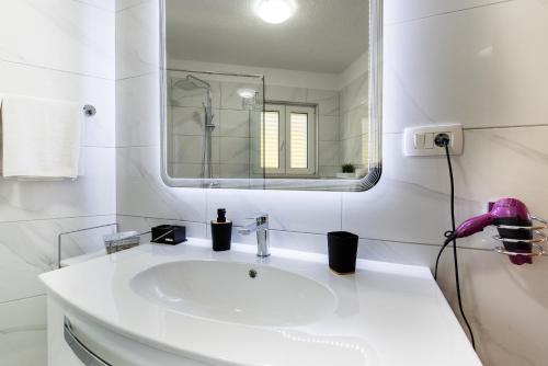 a white bathroom with a sink and a mirror at Apartment Gorana in Split