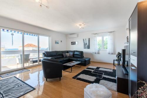 a living room with a black leather couch and a television at Apartment Gorana in Split