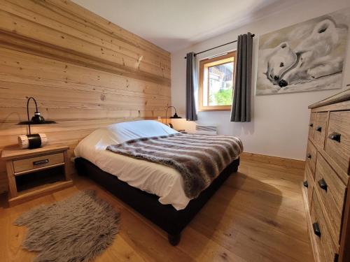 a bedroom with a bed and a wooden wall at Chalet Les Gets, 5 pièces, 6 personnes - FR-1-598-24 in Les Gets