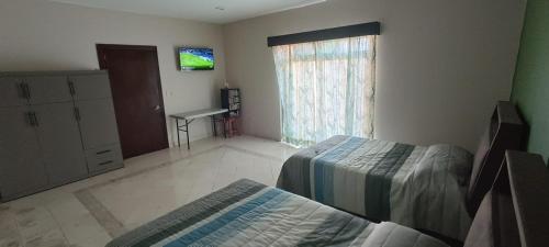 a bedroom with two beds and a television in it at Agradable Habitación Ojo de agua in Orizaba