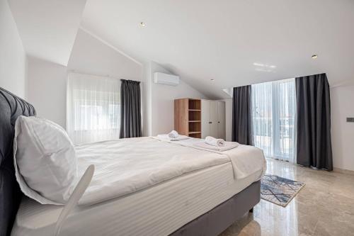 a white bedroom with a large bed and windows at Belek Deluxe Suit in Belek